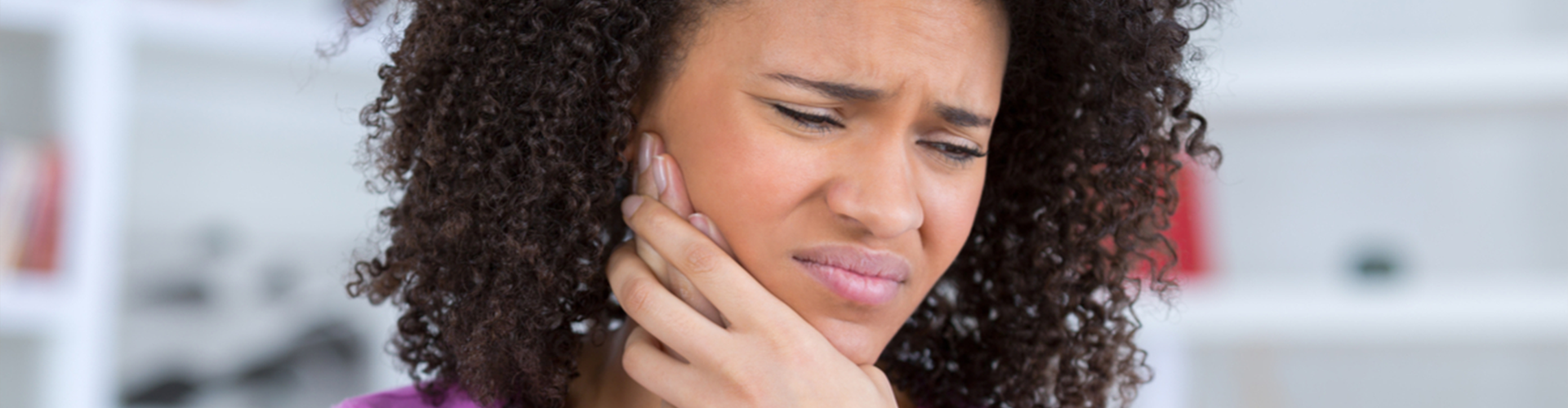 unhappy woman holding one side of her face 