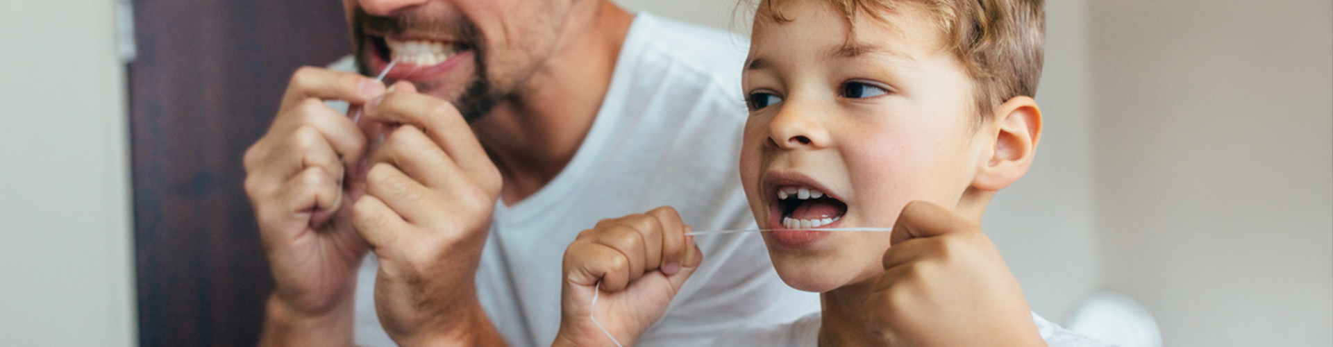 dad and son flossing teeth together 