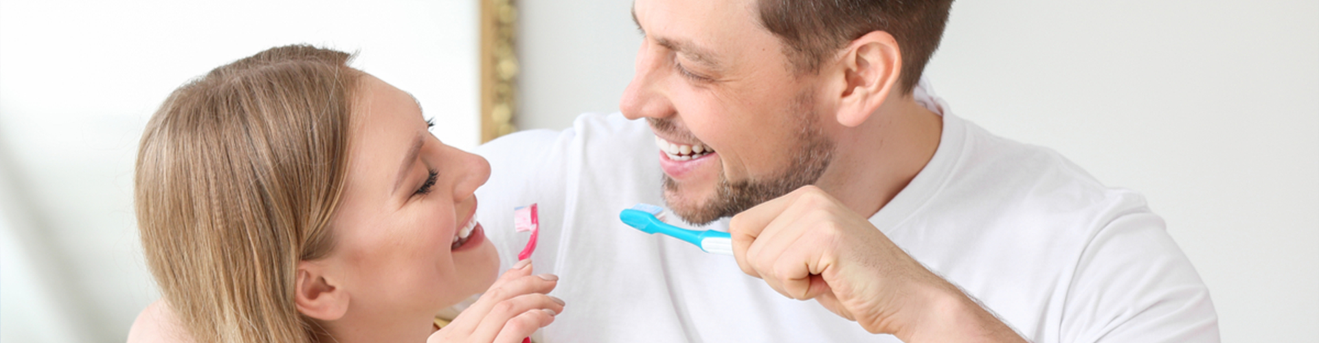 Couple brushing teeth and smiling at each other