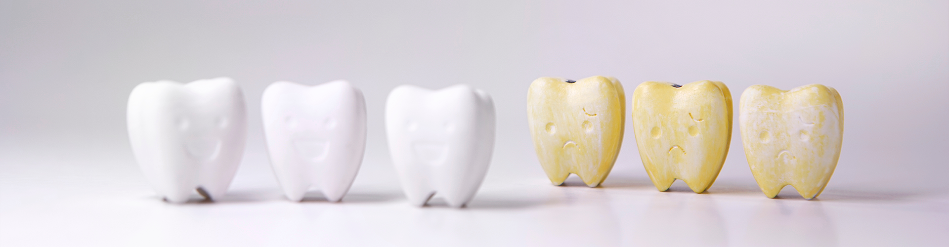 models of white teeth and yellow teeth with faces
