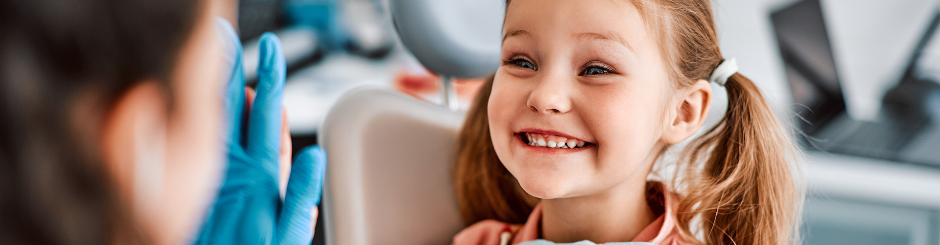 smiling girl holding stuffed bunny high-fiving dentist
