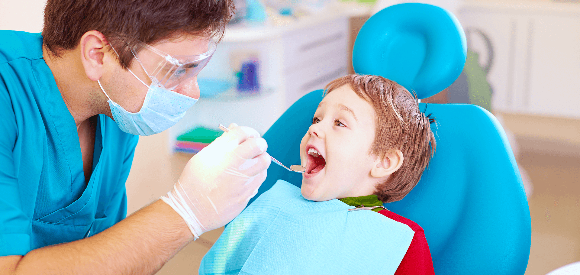 A kid with mouth open being examined by the dentist.