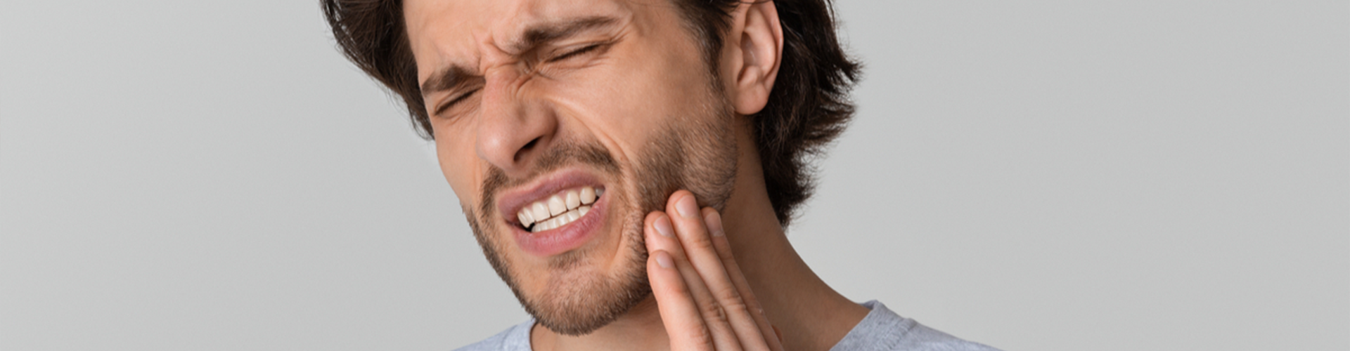 man holding the side of his face clenching 