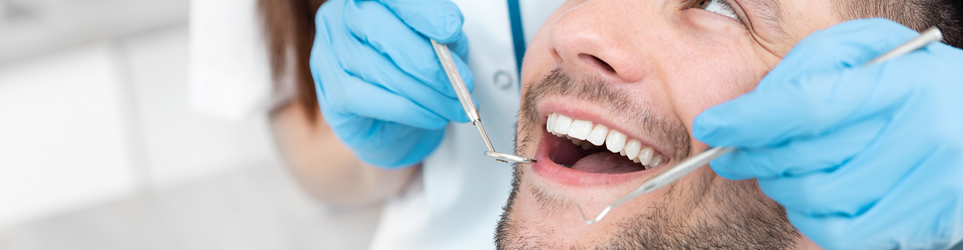 dentist holding dental tools beside smiling man's mouth