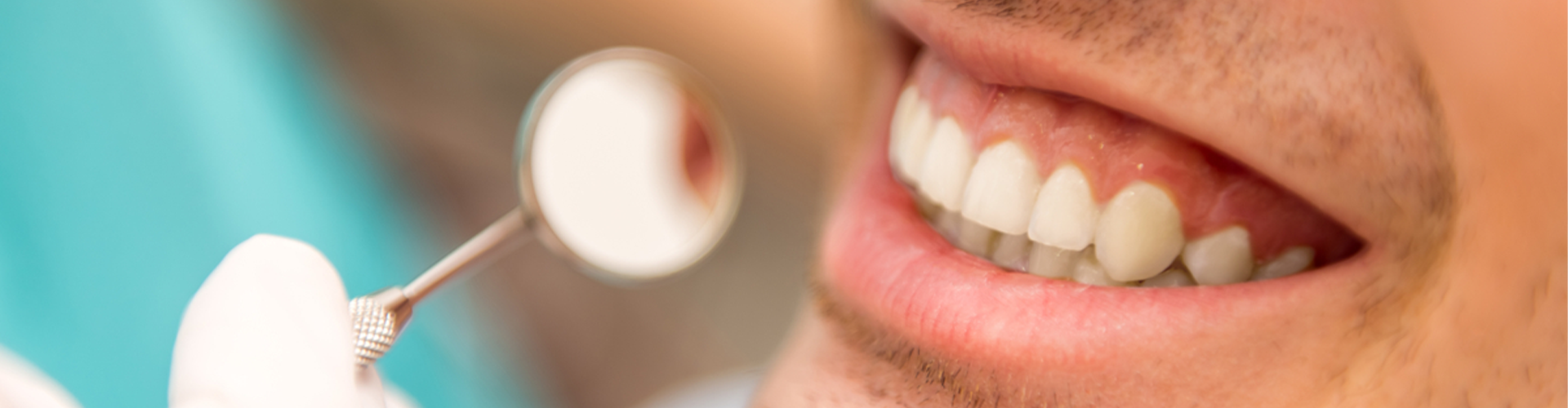 Man smiling with mirror to his teeth