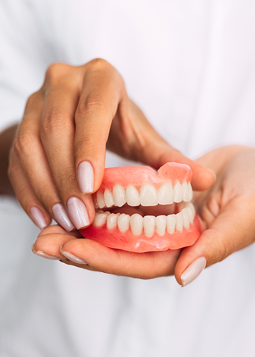 Hands holding a set of dentures.