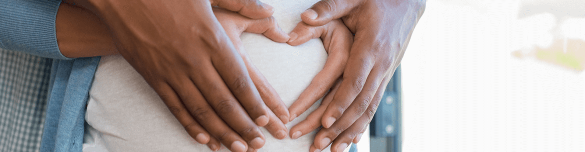 pregnant womans belly with her and her husbands hand on it