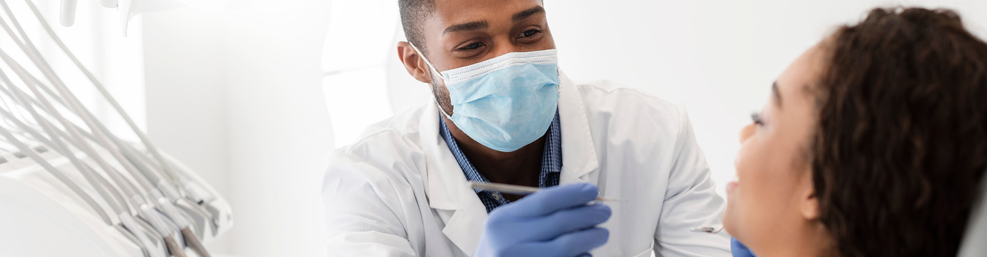 dentist holding dental tool speaking with patient in dental chair