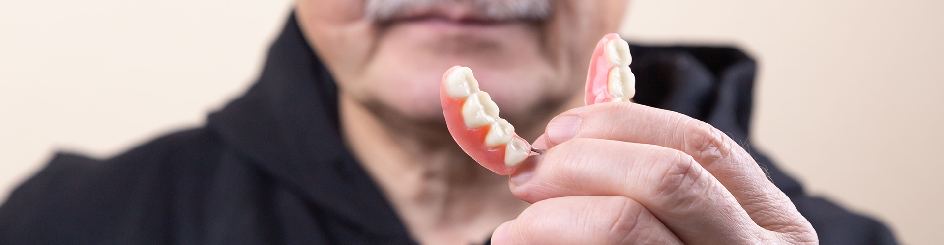 older man holding denture
