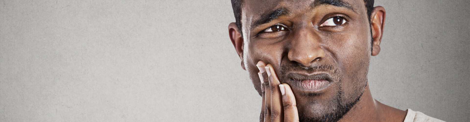 Man holding side of his face frowning