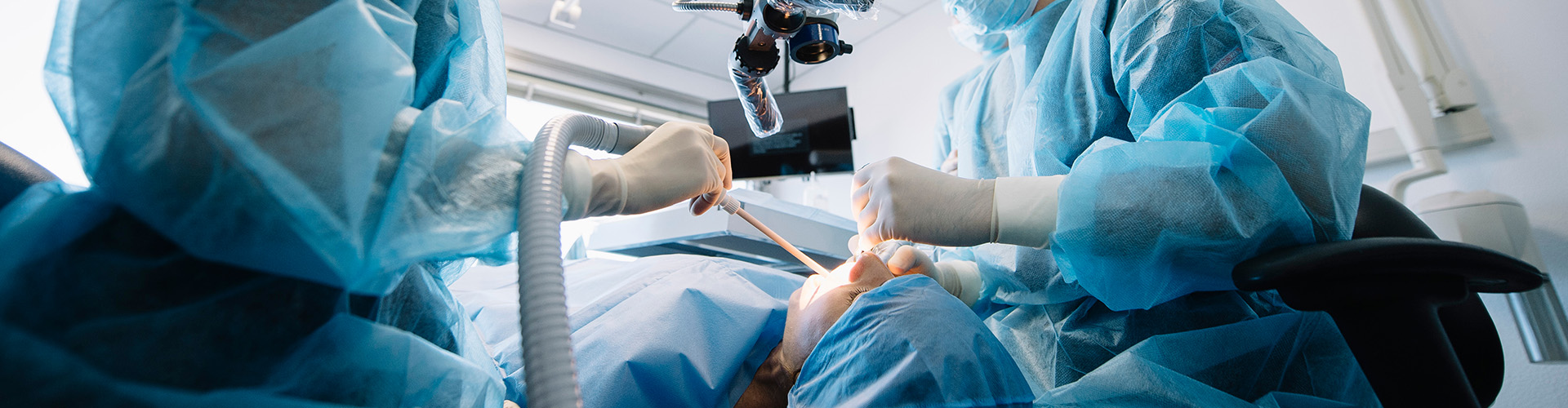 two dentists using dental tool in patient's mouth