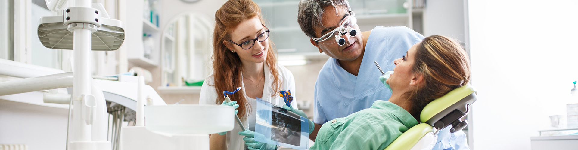 two dental professionals looking at patient in chair