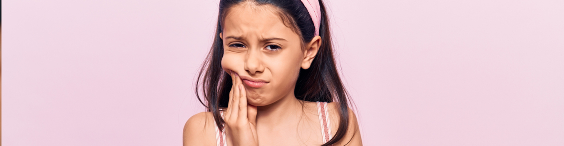Young girl holding the side of her mouth frowning