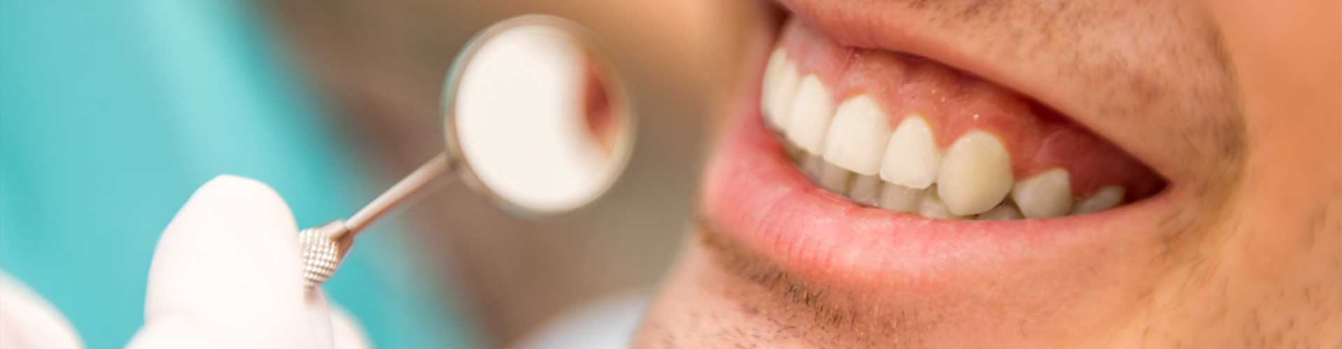 mouth smiling with mini mirror held up to teeth