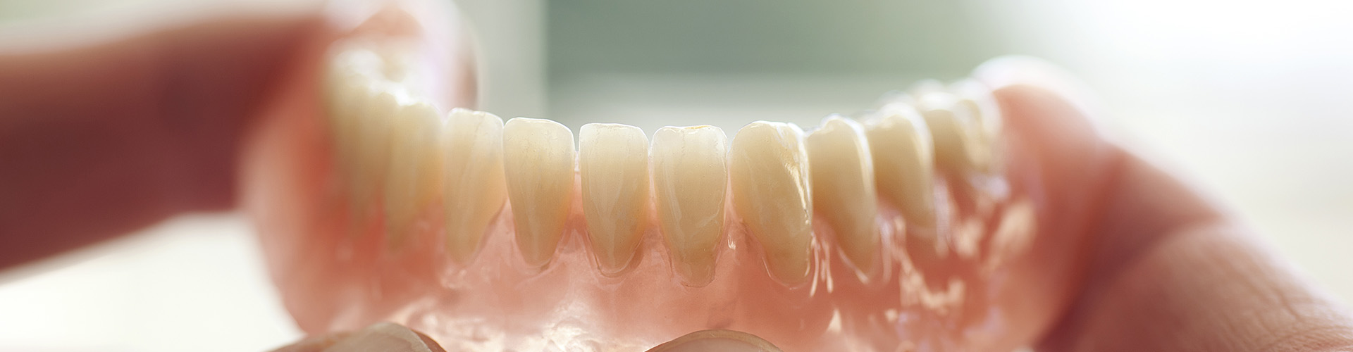 fingers holding lower denture