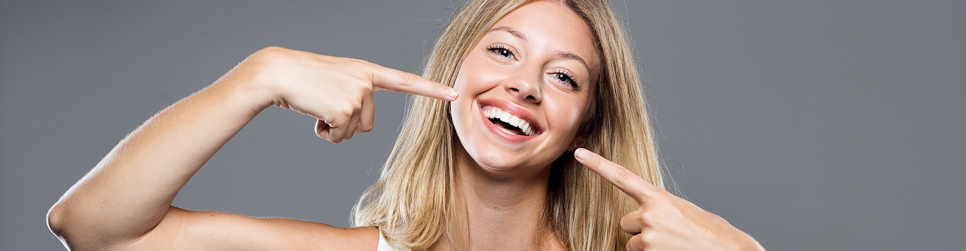 woman pointing at her smile with both hands