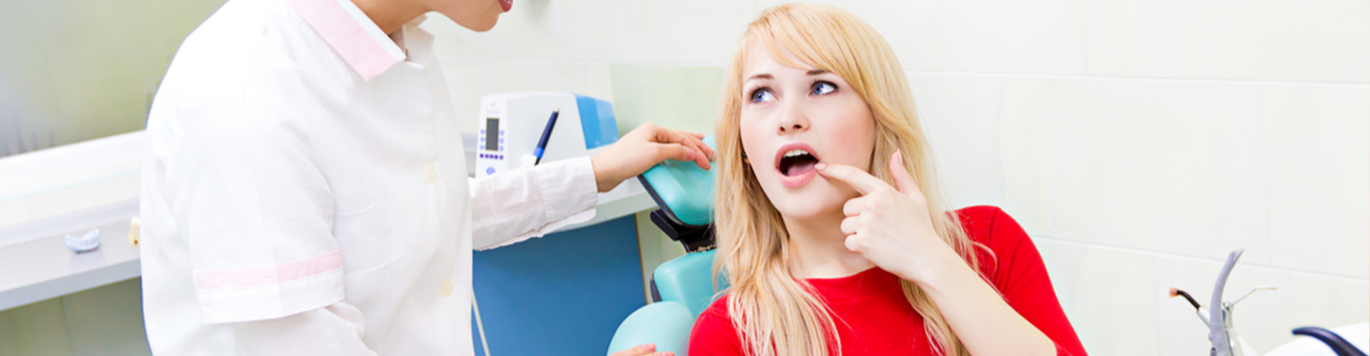 Dentist standing over patient who is sitting in the chair pointing to her tooth