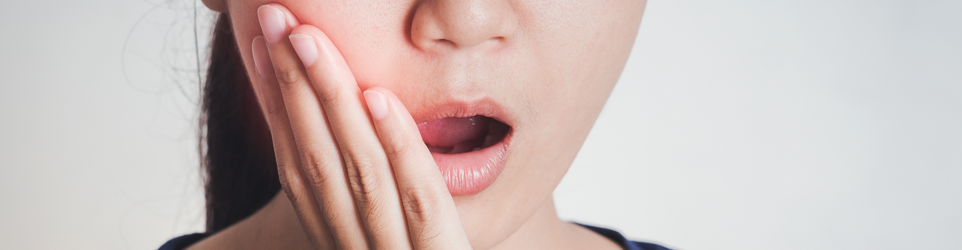 woman holding cheek in pain