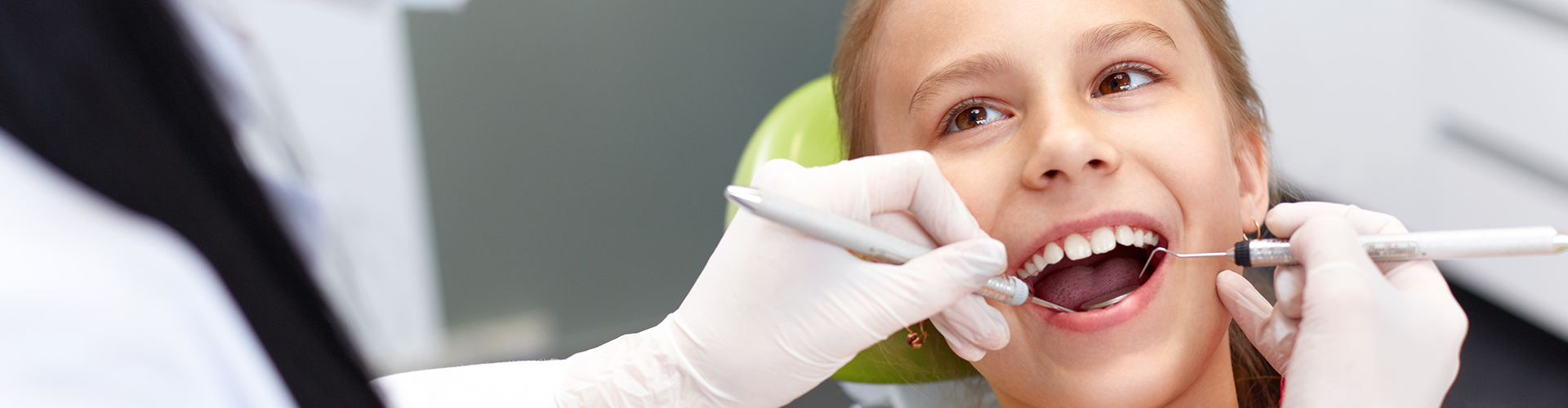 dentist using dental tools in child's mouth