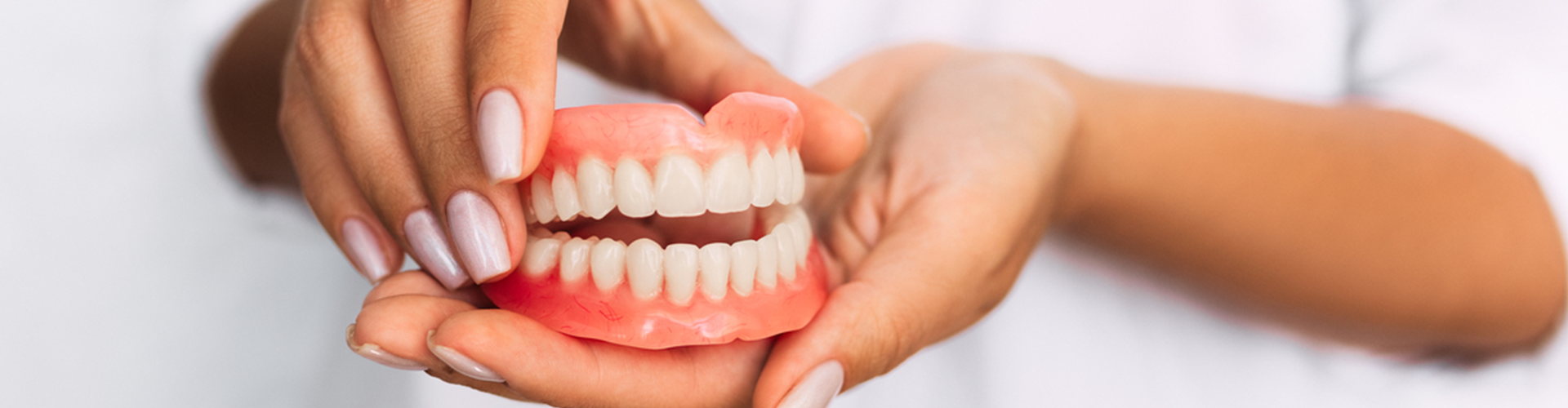 two hands holding dentures