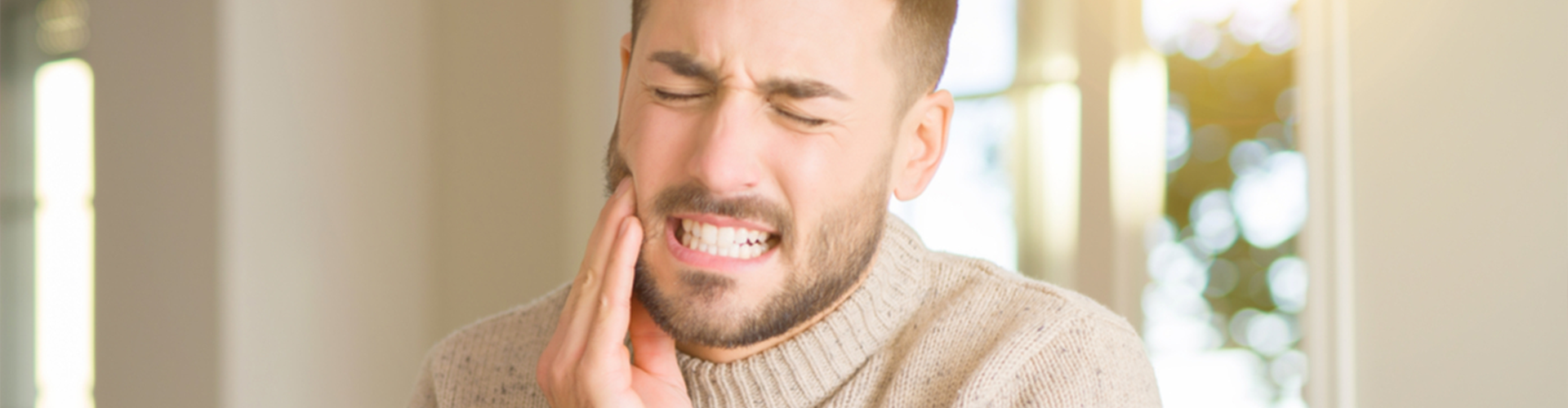 Man clenching his teeth holding the right side of his face
