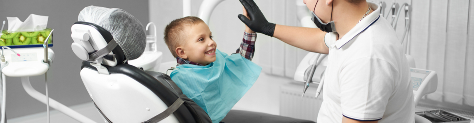 Child in dentist chair giving a high five to the doctor