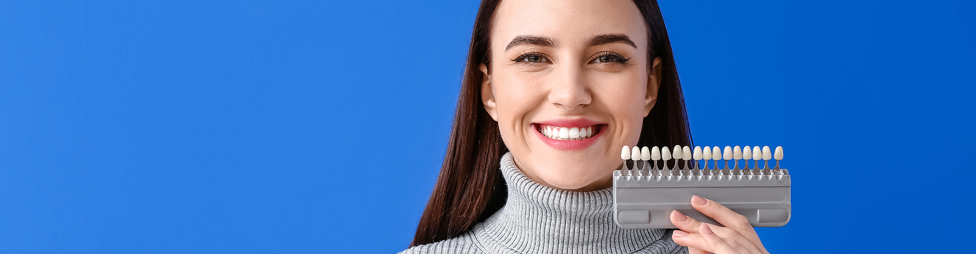 woman holding color-matching tool against her teeth