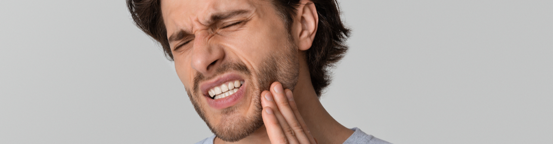 Man holding the side of his face clenching his teeth 
