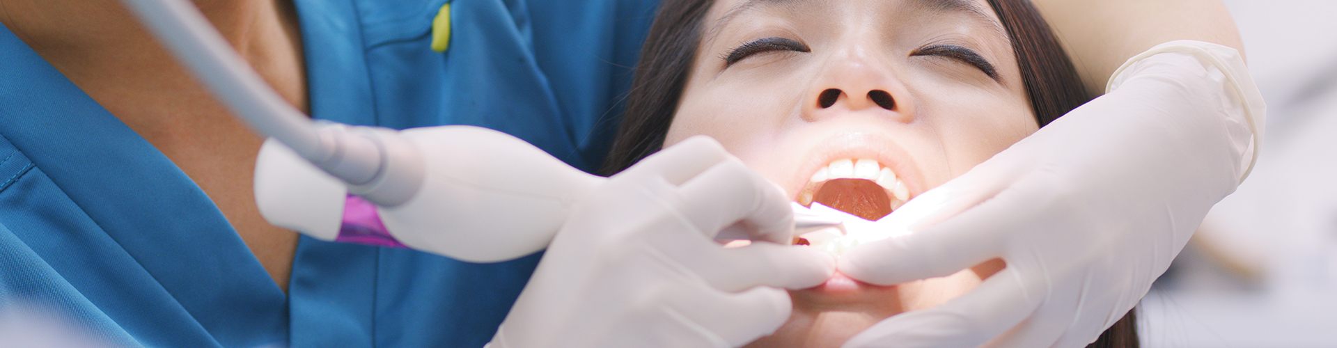 hands cleaning the teeth of a woman